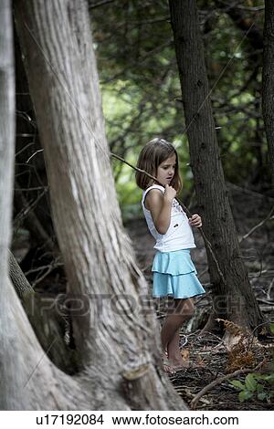 Picture - Girl walking through woods holding stick, Ontario. Fotosearch