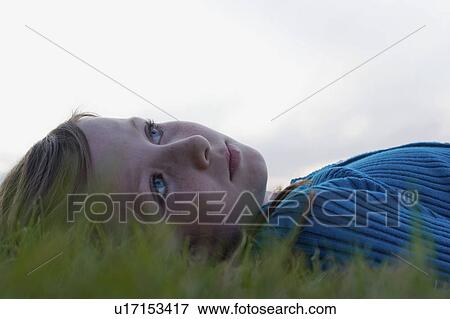 Stock Photo - Headshot, eight year old girl lying in grass looking upward, Winnipeg, Canada. Fotosearch