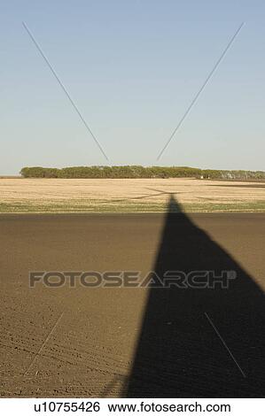 Stock Photograph - Long shadow of wind turbine on ground. Fotosearch