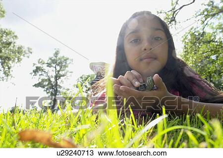 Stock Image - Low angle view, eight year old girl lying in grass with turtle, Winnipeg, Canada. Fotosearch