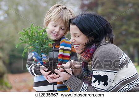 Stock Photo - Mother and young boy holding small tree ready to plant, Vancouver, British Columbia. Fotosearch