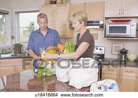 Picture - Senior couple unloads cloth grocery bags, Winnipeg, Canada. Fotosearch