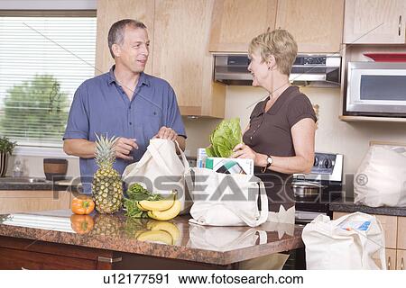 Stock Image - Senior couple unloads cloth grocery bags, Winnipeg, Canada. Fotosearch