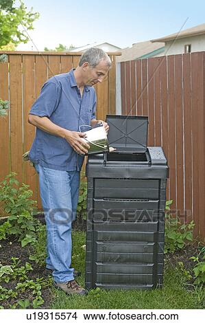 Picture - Senior man empties kitchen scraps into composter, Winnipeg, Canada. Fotosearch