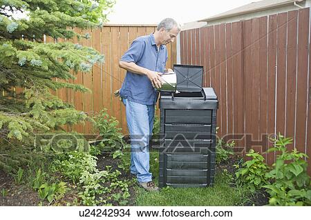 Picture - Senior man empties kitchen scraps into composter, Winnipeg, Canada. Fotosearch