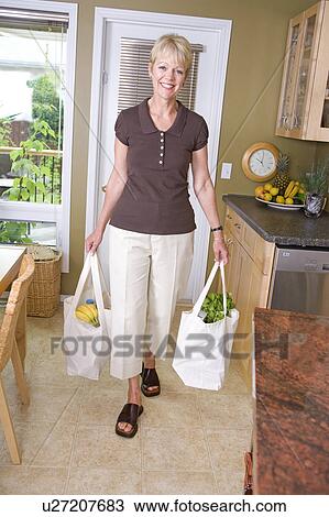 Stock Image - Senior woman carrying groceries in cloth bags, Winnipeg, Canada. Fotosearch