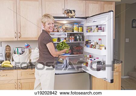 Senior woman unloads cloth grocery bags into refridgerator, Winnipeg, Canada View Large Photo Image Stock Image - Senior woman unloads cloth grocery bags into refridgerator, Winnipeg, Canada. Fotosearch