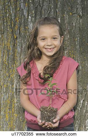 Seven year old girl holding seedling beside tree, Winnipeg, Canada View Large Photo Image Stock Photography - Seven year old girl holding seedling beside tree, Winnipeg, Canada. Fotosearch