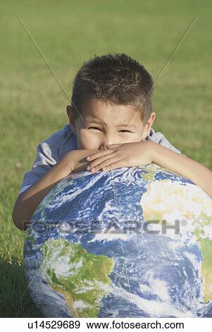 Stock Photo - Six year old boy leaning on inflatable globe in park, Winnipeg, Canada. Fotosearch