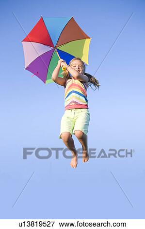 Stock Photo - Six year old girl jumping with umbrella, Winnipeg, Canada. Fotosearch