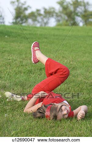 Stock Photo - Six year old girl rolling in grass, Winnipeg, Canada. Fotosearch