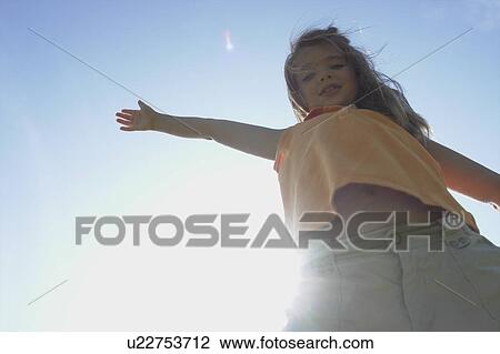 Stock Image - Sunflare, six year old girl with arms outstretched, Winnipeg, Canada. Fotosearch