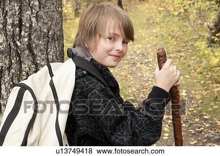 Stock Photo - Ten year old boy beside tree, wearing hemp backpack, Lake Katherine, Riding Mountain National Park, Manitoba. Fotosearch