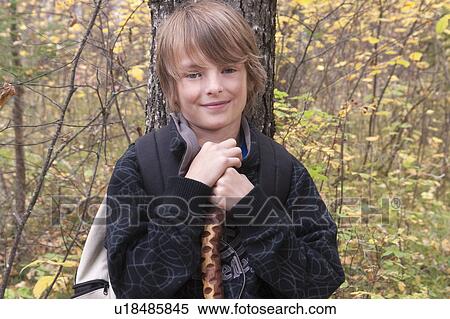 Stock Photography - Ten year old boy beside tree, wearing hemp backpack, Lake Katherine, Riding Mountain National Park, Manitoba. Fotosearch