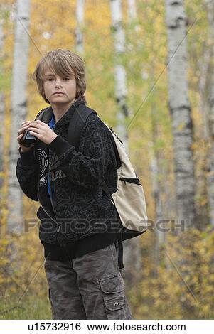 Stock Photograph - Ten year old boy holding binoculars wearing hemp backpack, Lake Katherine, Riding Mountain National Park, Manitoba. Fotosearch