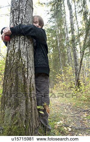 Stock Image - Ten year old boy hugging tree in woods, Lake Katherine, Riding Mountain National Park, Manitoba. Fotosearch