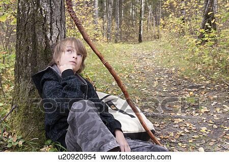 Ten year old boy seated leaning on tree beside trail, Lake Katherine, Riding Mountain National Park, Manitoba View Large Photo Image Picture - Ten year old boy seated leaning on tree beside trail, Lake Katherine, Riding Mountain National Park, Manitoba. Fotosearch