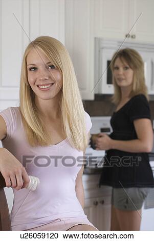 Stock Image - Two women in kitchen, one holding compact flourescent light bulb, Brandon, Canada. Fotosearch