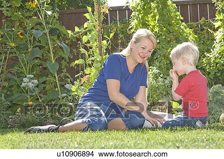 Picture - Two year old boy with mother shows eats beans from backyard, Winnipeg, Canada. Fotosearch