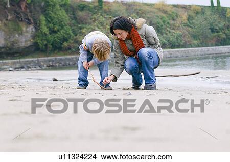 Woman and boy examine objects on beach, Vancouver, British Columbia View Large Photo Image Picture - Woman and boy examine objects on beach, Vancouver, British Columbia. Fotosearch