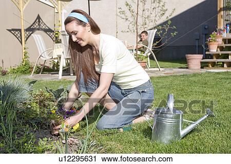 Stock Image - Woman working in backyard garden, Winnipeg, Canada. Fotosearch