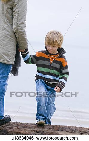 Young boy holding woman's hand as they walk on beach, Vancouver, British Columbia View Large Photo Image Stock Photograph - Young boy holding woman's hand as they walk on beach, Vancouver, British Columbia. Fotosearch