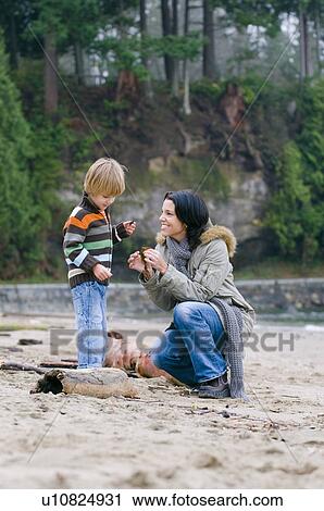 Young woman and boy examining sticks on beach, Vancouver, British Columbia View Large Photo Image Stock Image - Young woman and boy examining sticks on beach, Vancouver, British Columbia. Fotosearch