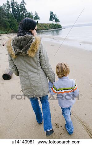 Stock Image - Young woman and boy walking on beach, Vancouver, British Columbia. Fotosearch