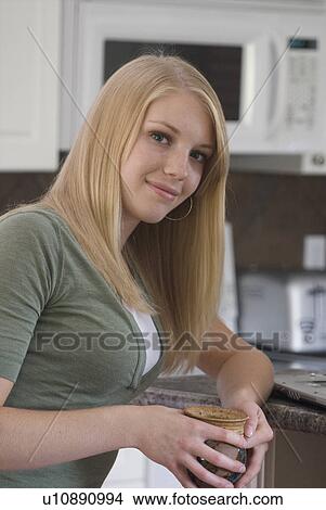 Young woman holding coffee mug in kitchen, Brandon, Canada View Large Photo Image Picture - Young woman holding coffee mug in kitchen, Brandon, Canada. Fotosearch
