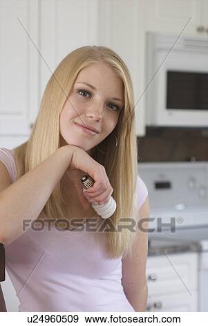 Young woman holding compact fluorescent bulb in kitchen, Brandon, Canada View Large Photo Image Stock Photo - Young woman holding compact fluorescent bulb in kitchen, Brandon, Canada. Fotosearch