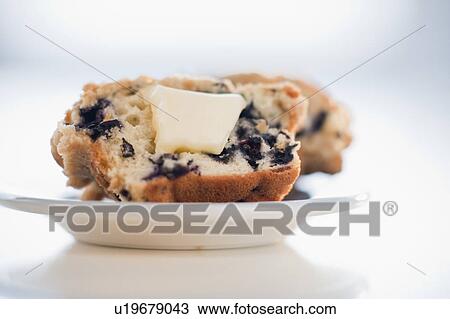 Stock Image - A blueberry muffin with butter. Fotosearch