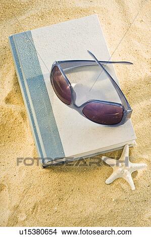 A book with sunglasses on sand View Large Photo Image Picture - A book with sunglasses on sand. Fotosearch