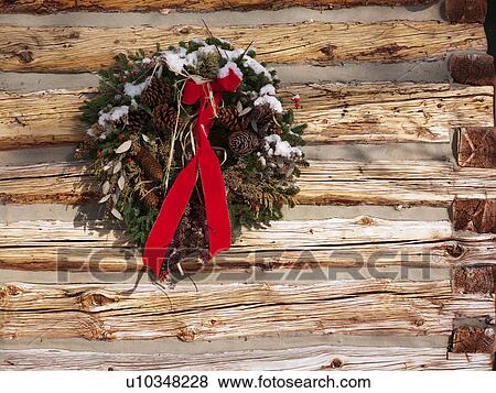 Stock Photo - A Christmas wreath on a cabin wall. Fotosearch