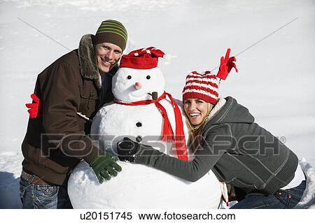 A couple making a snowman View Large Photo Image Stock Photography - A couple making a snowman. Fotosearch