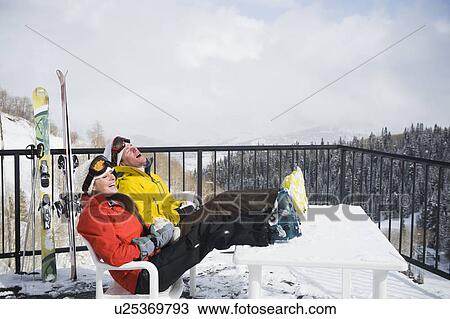 A couple relaxing on deck at ski resort View Large Photo Image Stock Image - A couple relaxing on deck at ski resort. Fotosearch