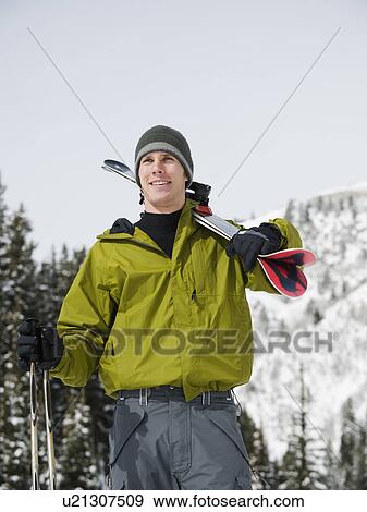 Stock Photo - A downhill skier carrying skis. Fotosearch