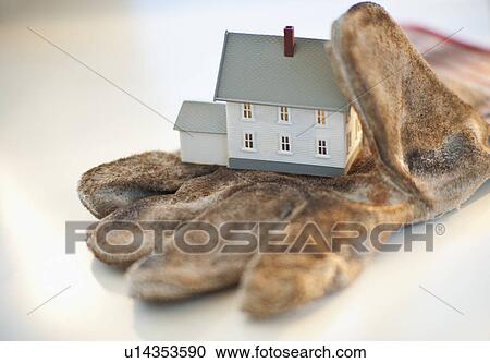 Stock Image - A glove with a toy house. Fotosearch