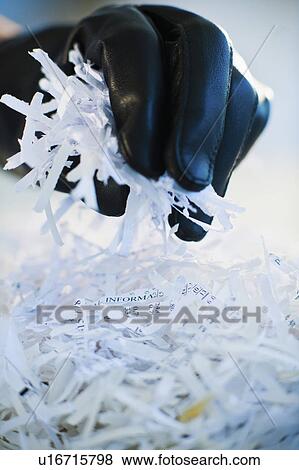 Stock Photo - A gloved hand going through shredded papers. Fotosearch