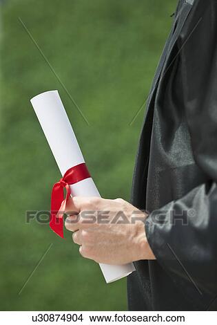 A graduate holding a diploma View Large Photo Image Picture - A graduate holding a diploma. Fotosearch