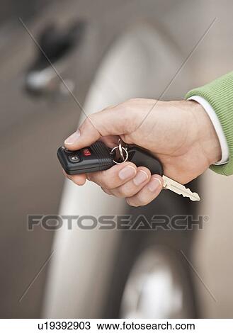 Stock Image - A hand holding a car remote key. Fotosearch