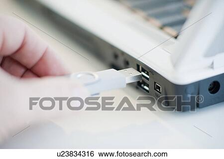 Stock Photograph - A hand plugging in a universal serial bus. Fotosearch