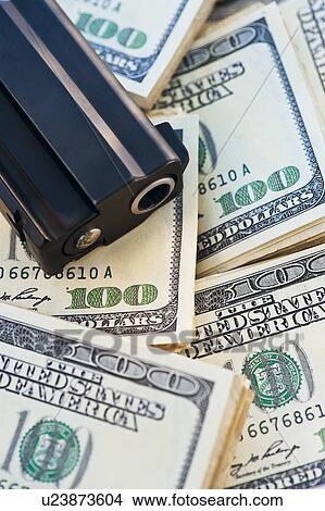 Picture - A handgun on stacks of money. Fotosearch