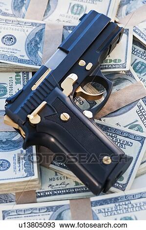 Stock Image - A handgun on stacks of money. Fotosearch