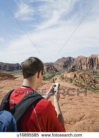 Stock Photography - A man at Red Rock holding a GPS. Fotosearch