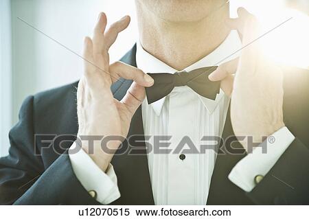 Stock Photography - A man in a tuxedo fixing his bowtie. Fotosearch