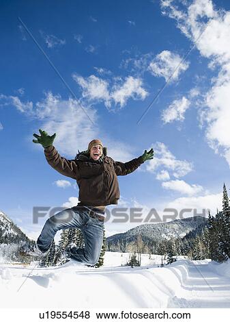 Stock Photo - A man outdoors in snowy surroundings jumping. Fotosearch