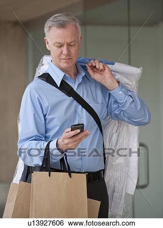 Stock Photograph - A man with dry cleaning and shopping bags. Fotosearch