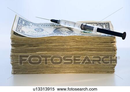 Stock Photography - A syringe on a stack of banknotes. Fotosearch