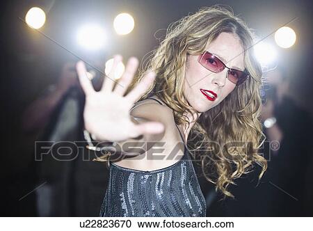 Stock Image - A woman being photographed by paparazzi. Fotosearch