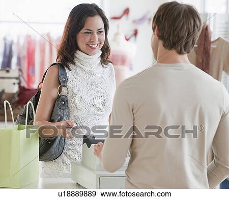 Stock Photo - A woman buying clothing at a store. Fotosearch
